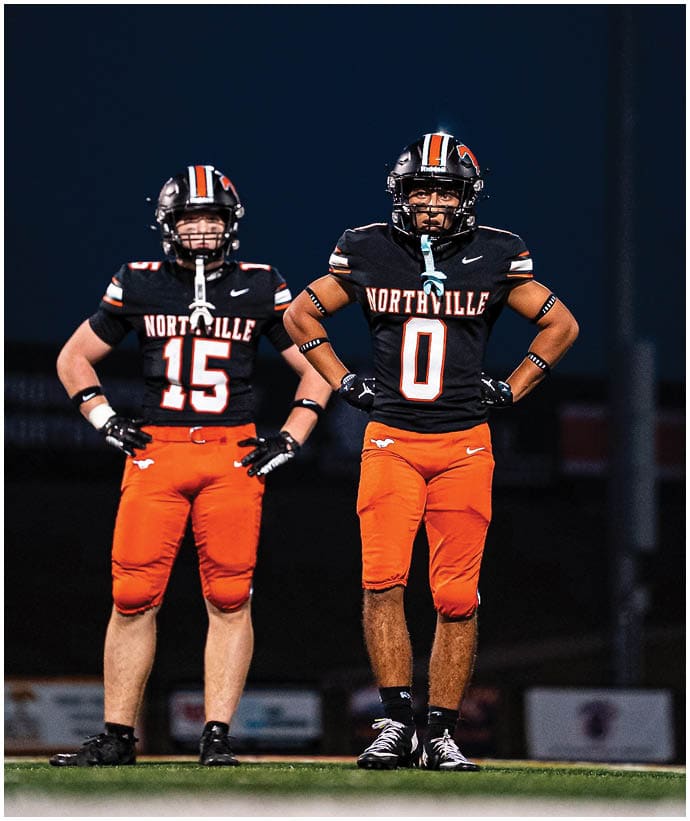 A group of football players wearing black and white uniforms. Description generated by AI