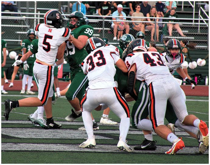 Three football players in blue and white uniforms running on a field. Description generated by AI