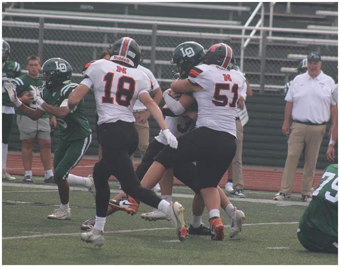Three football players in blue and white uniforms running on a field. Description generated by AI