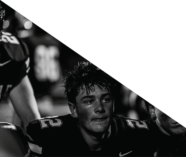 A group of football players kneeling on the field, some with their hands on their heads. AI generated content