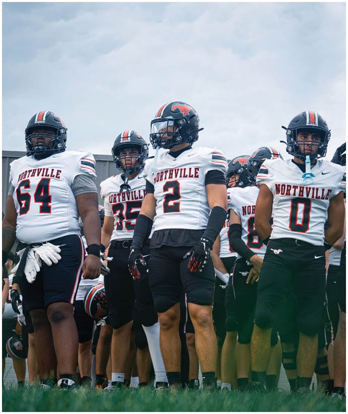 A group of football players wearing black and white uniforms. Description generated by AI