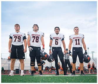 A group of football players wearing black and white uniforms. Description generated by AI