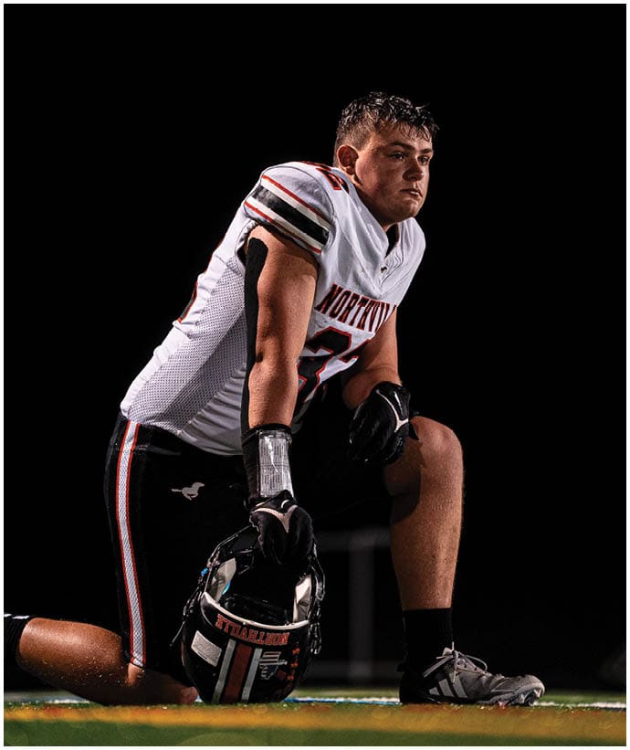 A group of football players wearing black and white uniforms. Description generated by AI