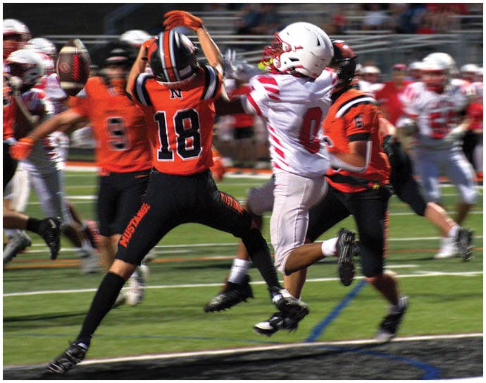 Three football players in blue and white uniforms running on a field. Description generated by AI