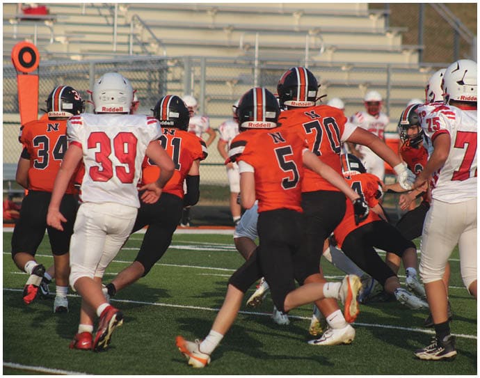 Three football players in blue and white uniforms running on a field. Description generated by AI