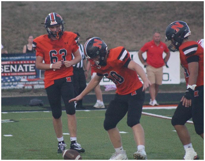 Three football players in blue and white uniforms running on a field. Description generated by AI