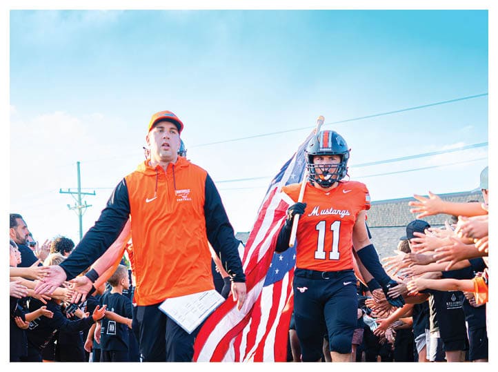 A group of football players on a field, one of them is running with a football. AI generated content