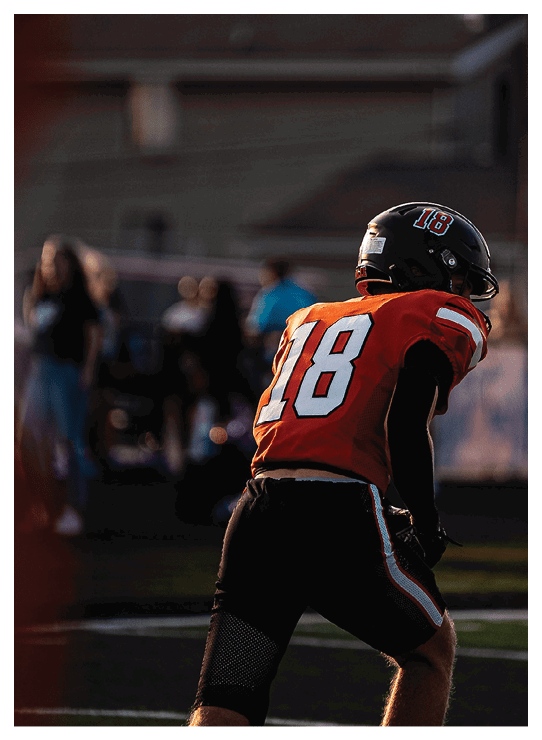 A football player wearing a helmet and white uniform is holding his helmet above his head. AI generated content