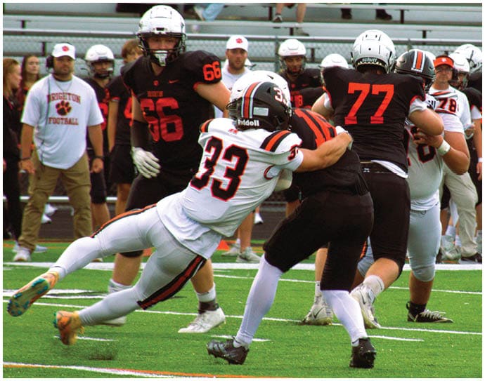 Three football players in blue and white uniforms running on a field. Description generated by AI