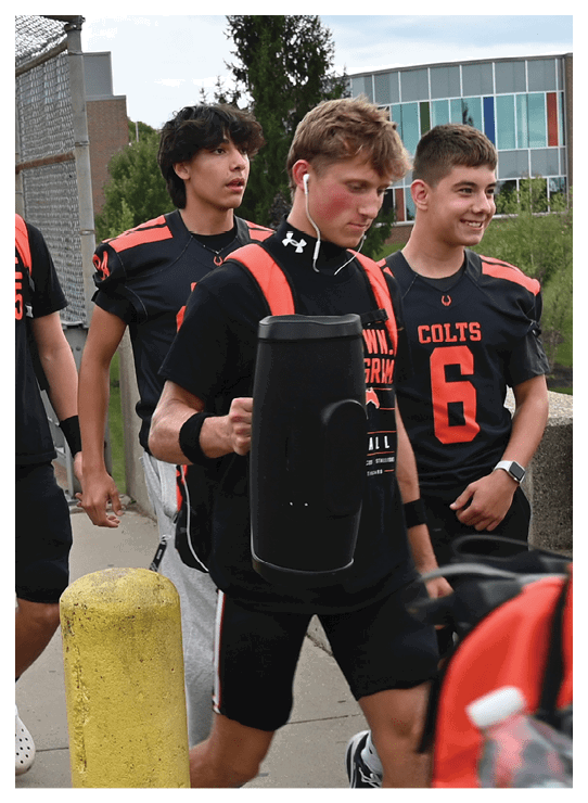A football player wearing a helmet and white uniform is holding his helmet above his head. AI generated content