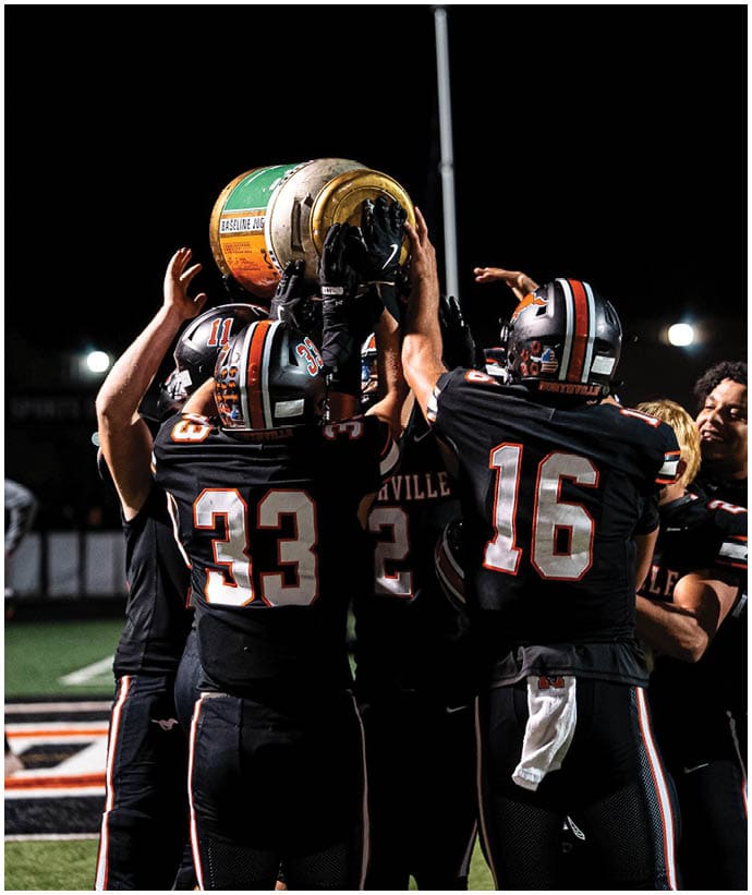 A group of football players wearing black and white uniforms. Description generated by AI