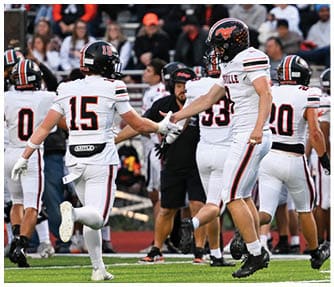 A group of football players wearing black and white uniforms. Description generated by AI