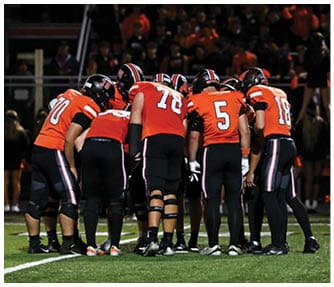 A group of football players wearing black and white uniforms. Description generated by AI