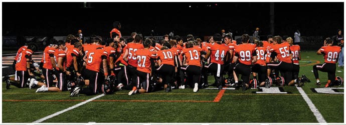 A group of football players on a field. Description generated by AI