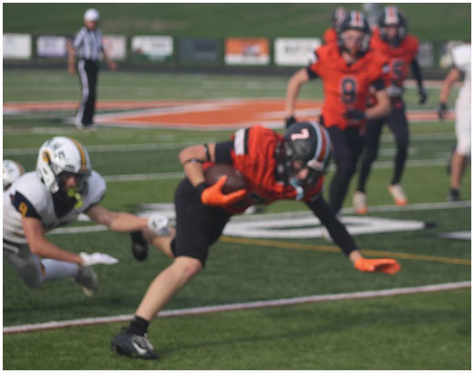 Three football players in blue and white uniforms running on a field. Description generated by AI