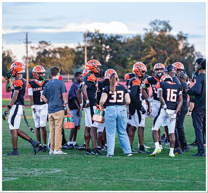A group of football players huddled together on the field. Description generated by AI