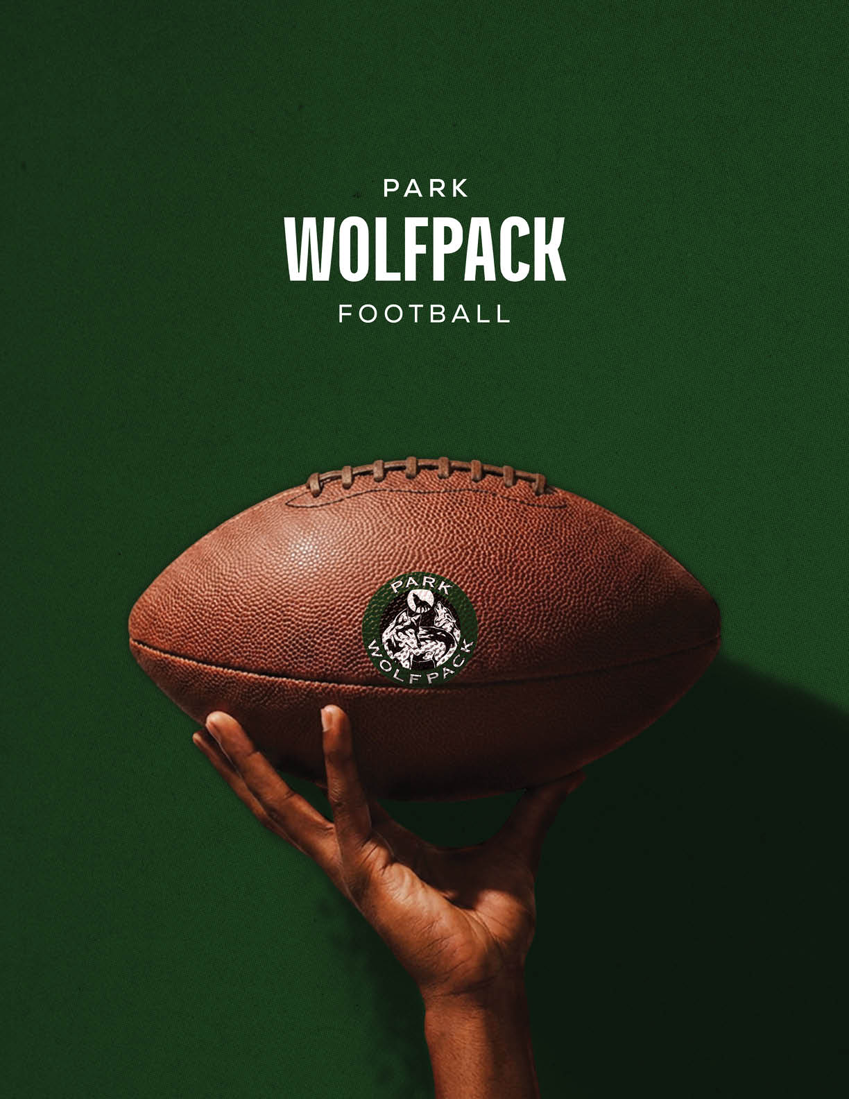 A hand is holding a brown football with a Park Wolfpack logo against a dark green background with the text “Park Wolfpack Football" above. Description generated by AI