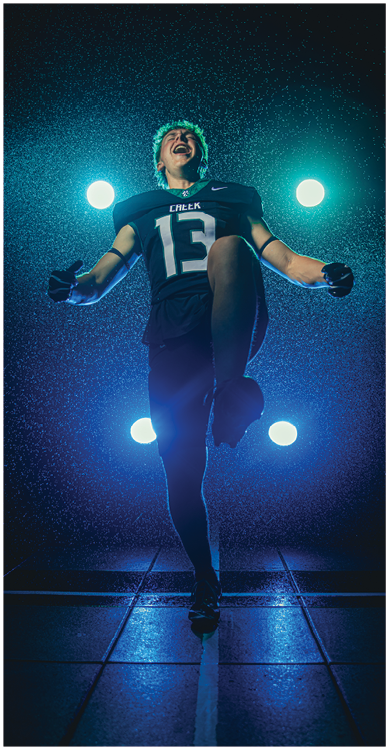 A person wearing a dark sports uniform with the number 13 is joyfully jumping or running on a wet tiled surface under bright stadium lights at night. Description generated by AI