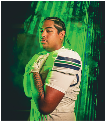 A person with braided hair wearing a white sports uniform and gloves poses confidently against a green smoky background. Description generated by AI
