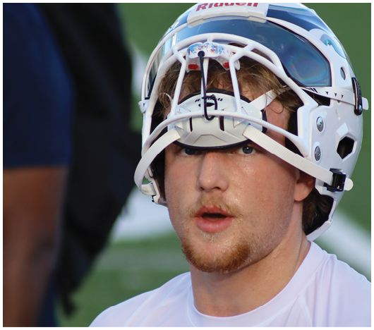 A person wearing a white sports helmet and white shirt appears focused and slightly open-mouthed, likely during a sports event. Description generated by AI