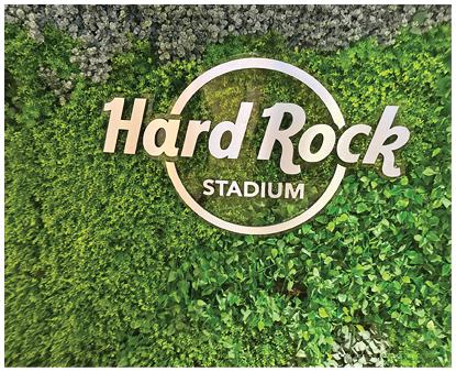 The Hard Rock Stadium logo is displayed on a lush green wall covered with various types of plants. Description generated by AI