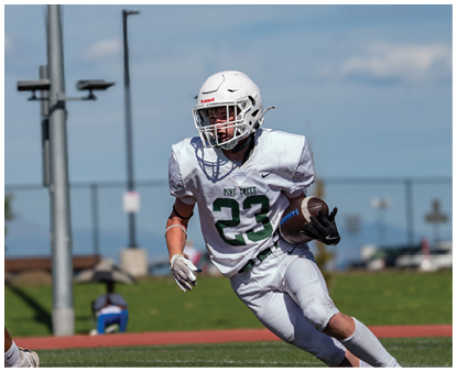 A person wearing a white football uniform with the number 23 and the words Pine Creek is running on a field while holding a football. Description generated by AI