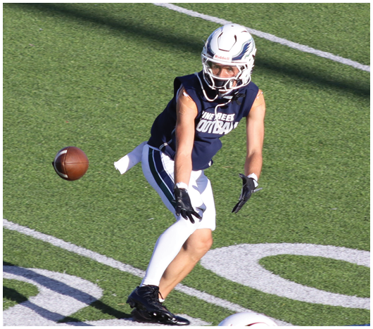 Two people wearing white football helmets with red faceguards and a red lion logo are focused and looking ahead. Description generated by AI