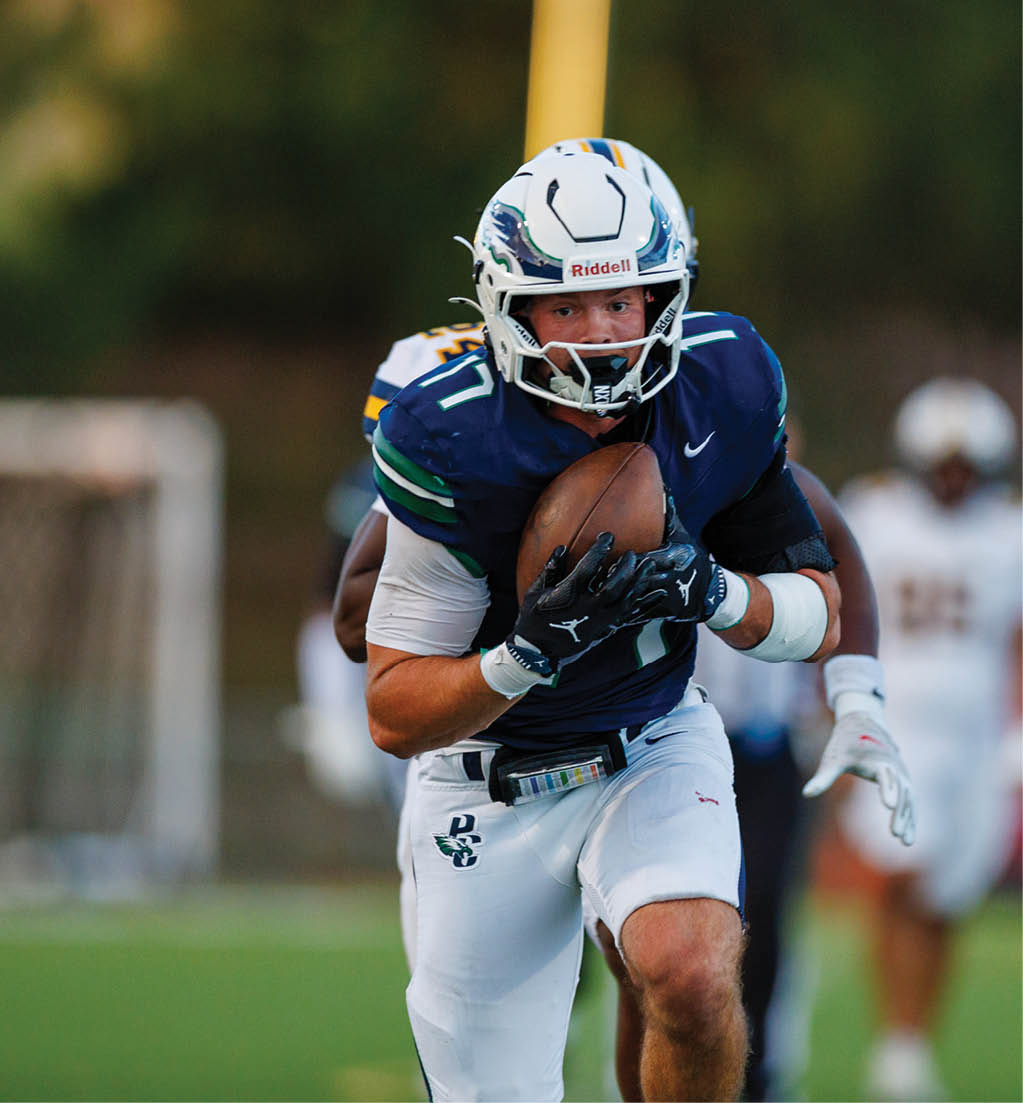 A person wearing a blue and white football uniform is running on a field while holding a football tightly. Description generated by AI