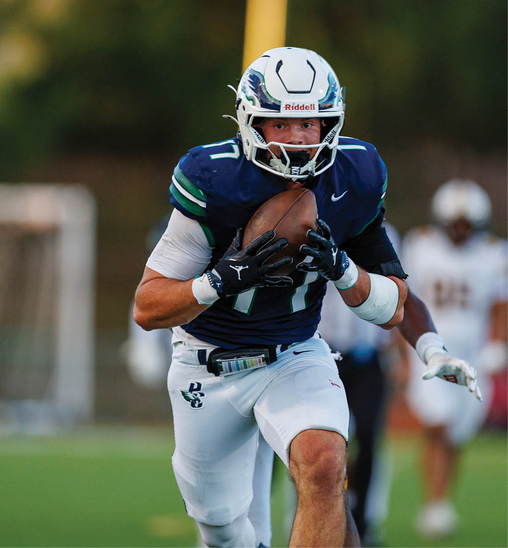 A person wearing a football uniform and helmet is running on a field while holding a football securely. Description generated by AI