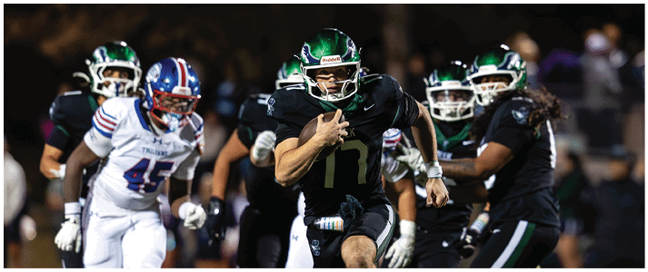 People in sports uniforms are running on a field during a nighttime football game. Description generated by AI