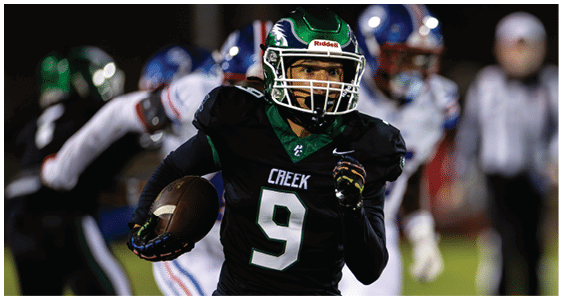A person wearing a black football uniform with the number 9 and the word “CREEK" is running with a football during a game. Description generated by AI