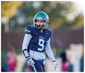 A person wearing a blue and green football uniform with the number nine stands on a field looking to the side. Description generated by AI