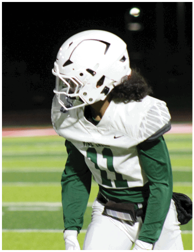 A close-up side view of a person wearing a white football helmet against a dark background. Description generated by AI