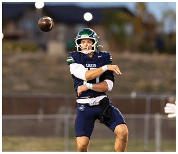 A person wearing a football uniform and helmet is throwing a football on a field during a game or practice. Description generated by AI