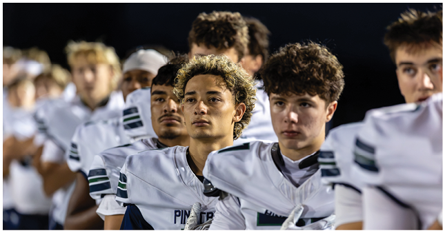 A line of people wearing white sports jerseys stand closely together, looking forward with serious expressions. Description generated by AI