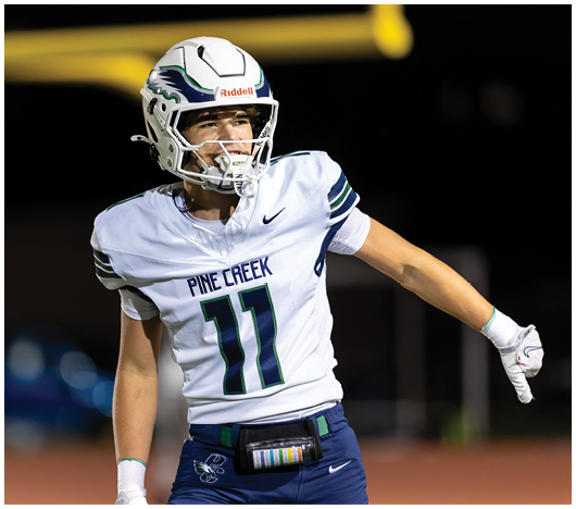 A person wearing a white football uniform with the number 11 and a helmet is on a field, appearing to be in motion or celebrating. Description generated by AI