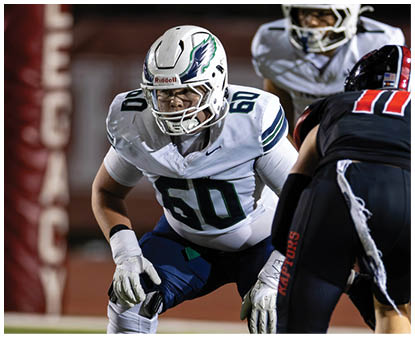 Several people in football uniforms are positioned on a field preparing for a play during a game. Description generated by AI