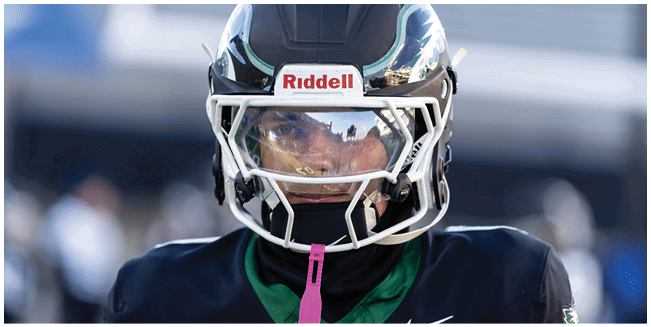 A person wearing a dark sports jersey and a white football helmet with a clear visor is looking forward. Description generated by AI
