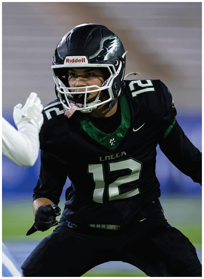 Two people in football uniforms are engaged in a play on a field, with one wearing a black jersey and helmet and the other in a white jersey and helmet. Description generated by AI