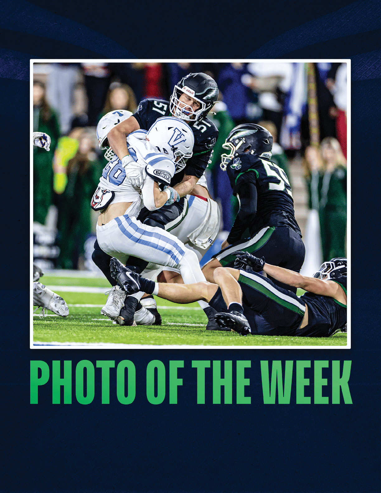 Several people in football uniforms are engaged in a tackle on a green field during a game with a crowd in the background. Description generated by AI