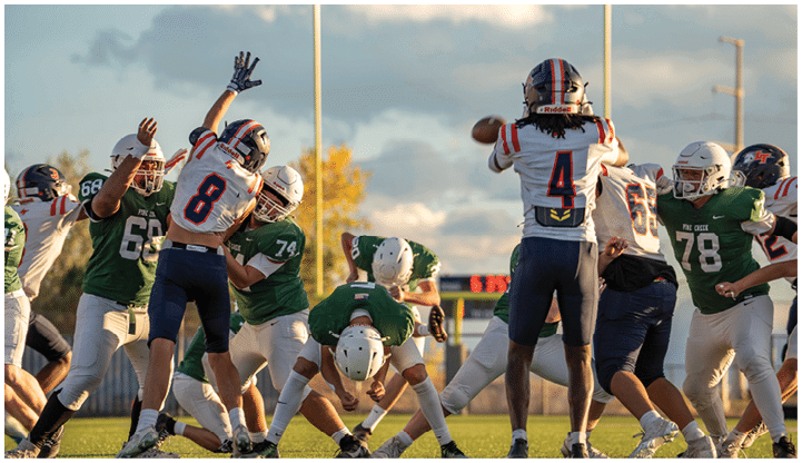 People in football uniforms are actively engaged in a play on a field during a game with one person preparing to throw the ball. Description generated by AI