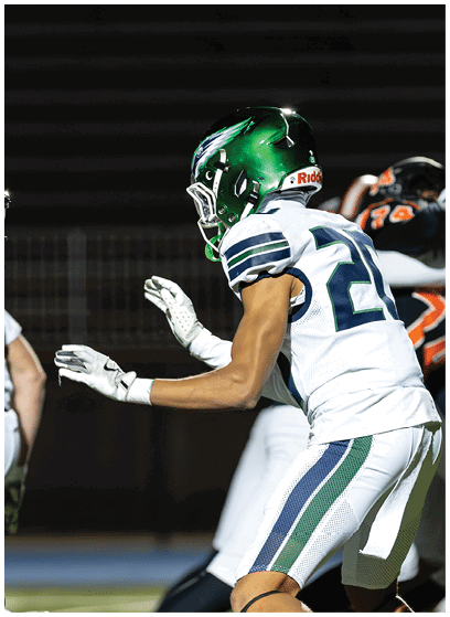 Two people in football uniforms and helmets are engaged in a play on a field at night, with one wearing a black jersey with the number 17 and the other in a white jersey with green accents. Description generated by AI