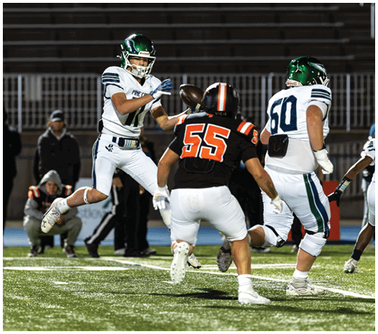 A group of people in football uniforms are actively playing on a field with one person in white jumping to catch a football while others in black and white uniforms move around. Description generated by AI