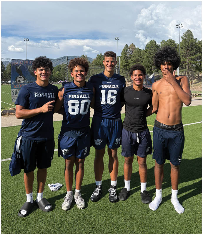 Three football players in blue and white uniforms running on a field. Description generated by AI