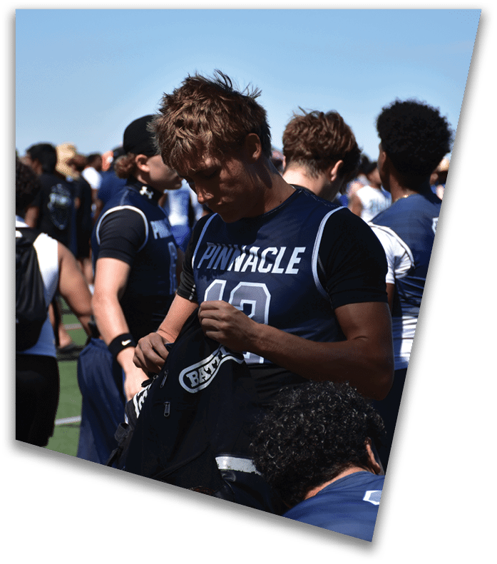 A person wearing a dark football uniform and helmet with “American Canyon" on the jersey is kneeling on one knee on a field at night. Description generated by AI