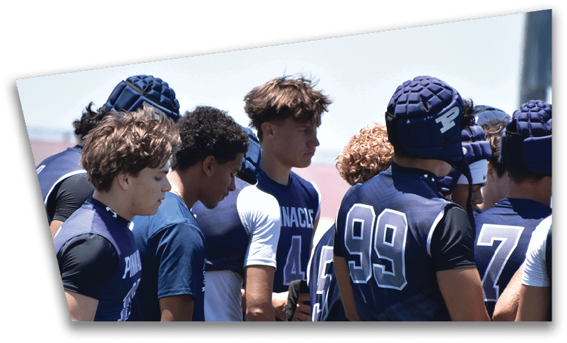 People wearing black American Canyon football uniforms and helmets are standing on a football field at night. Description generated by AI