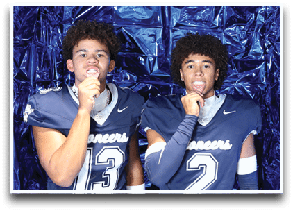 Three football players are standing on the field, one of them is smiling and wearing a black jersey with the number 55. AI generated content