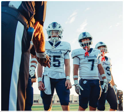 A group of football players huddled together on the field. Description generated by AI