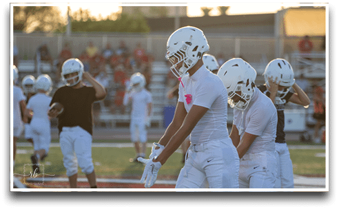 Three football players are standing on the field, one of them is smiling and wearing a black jersey with the number 55. AI generated content