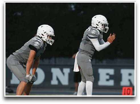Three football players are standing on the field, one of them is smiling and wearing a black jersey with the number 55. AI generated content